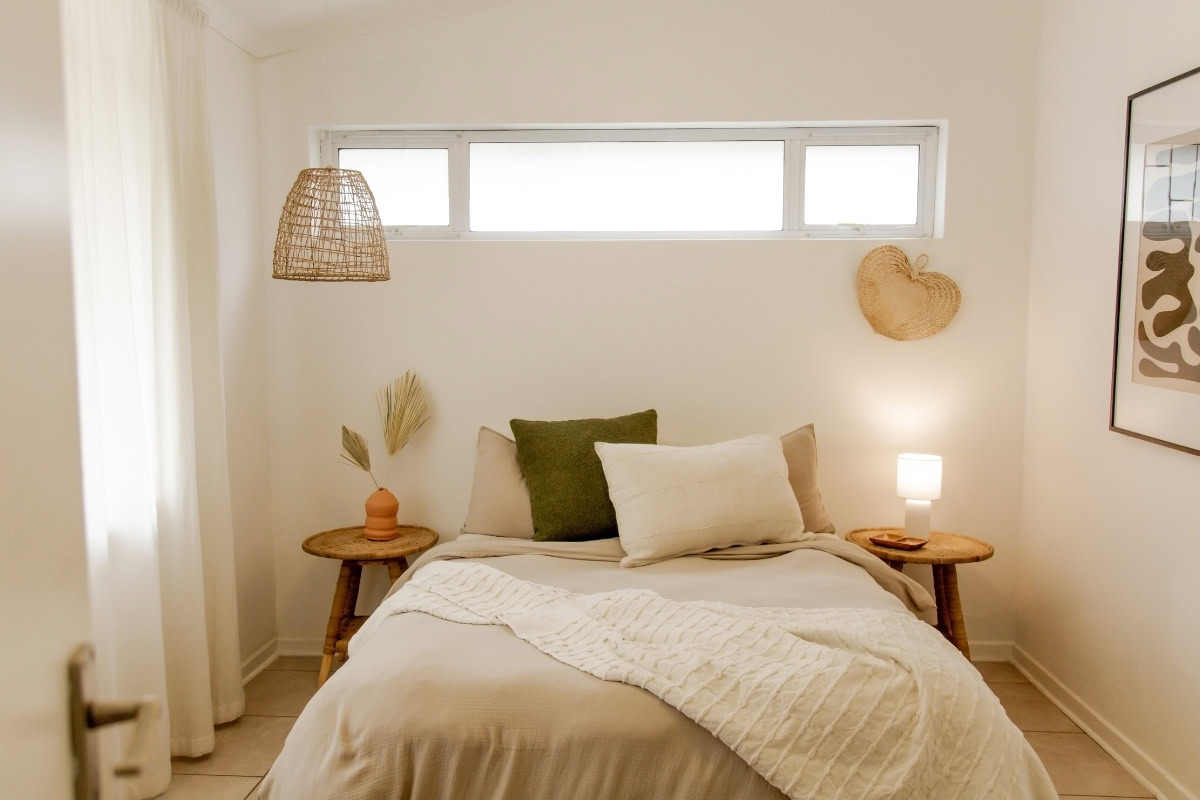Cozy sleep-friendly bedroom in Ankeny with neutral bedding, decorative pillows, soft lighting, and natural elements for a relaxing atmosphere.