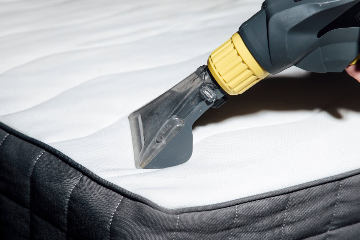 Vacuum cleaner attachment cleaning mattress surface, demonstrating proper care for mattress maintenance in Sioux Falls.