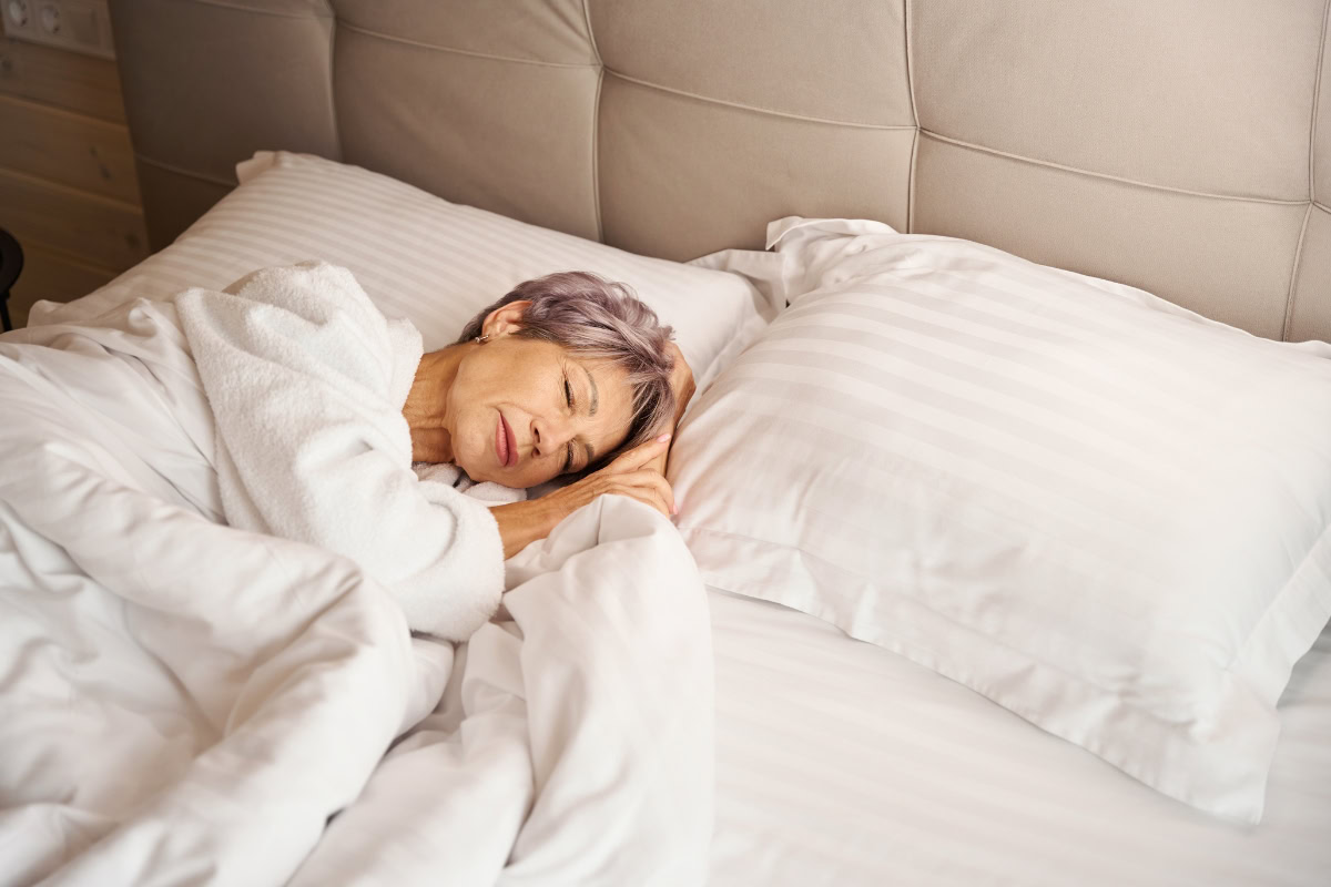 Senior woman peacefully resting in adjustable bed, promoting comfort and sleep quality for older adults.