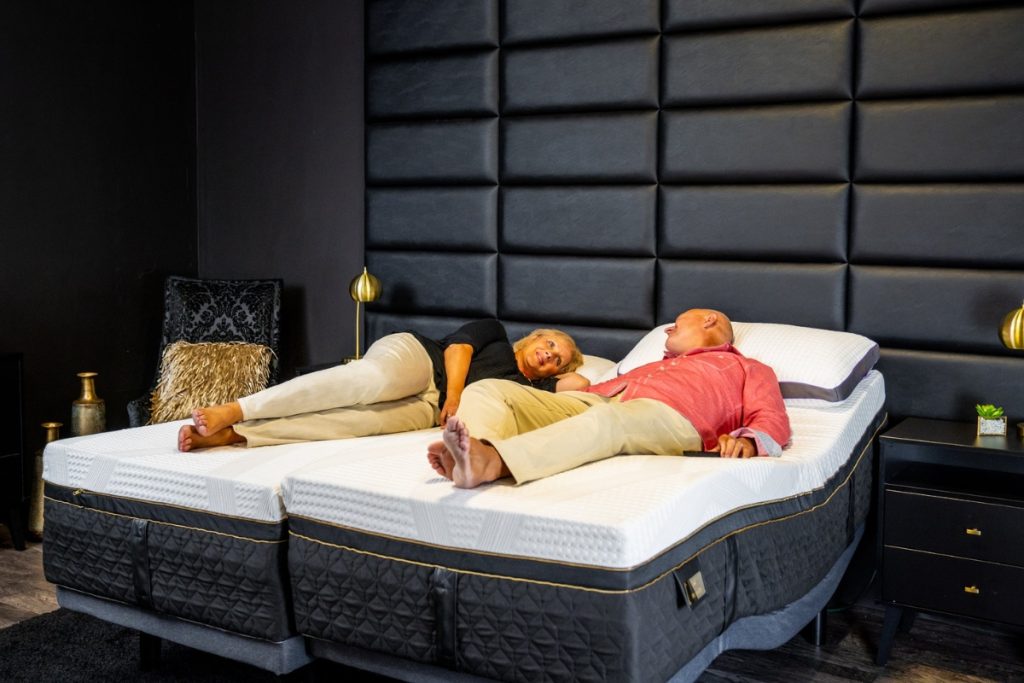 Couple lying on a gapless adjustable mattress, demonstrating comfort and seamless sleep in a modern bedroom setting.