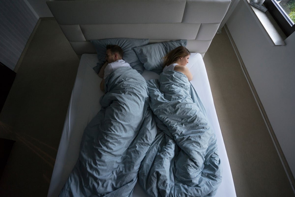 Couple sleeping side by side on a mattress, highlighting comfort and support for side sleepers, with soft bedding and a modern bedroom setting.